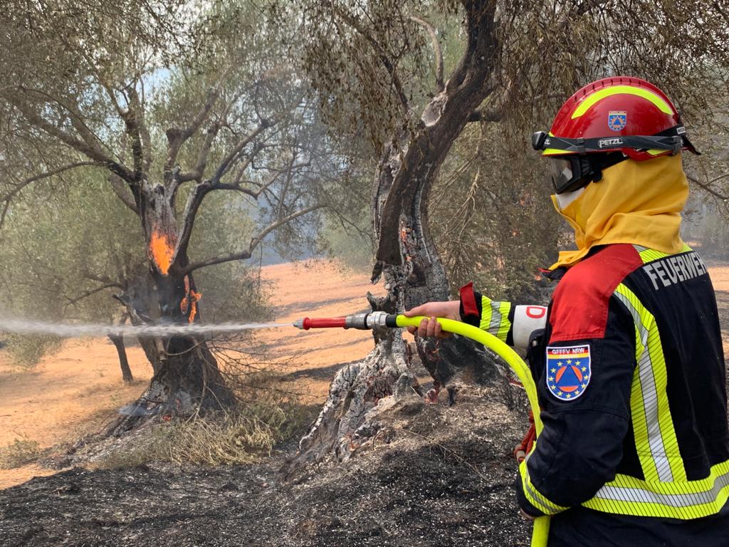 Ein Feuerwehrmann aus Deutschland löscht brennende Olivenbäume