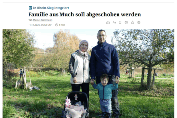 Das Bild zeigt eine Familie, die auf einer grünen Wiese im Freien steht. Im Vordergrund sitzt ein Baby in einer Babyschale mit einem Stofftier daran befestigt. Links daneben steht eine Frau mit heller Jacke, rechts ein Mann in dunkler Jacke, der ein kleines Kind an der Hand hält. Die Gesichter der Personen sind verpixelt. Im Hintergrund sind Bäume und ein Gartenschlauch, sowie weitere Menschen auf der Wiese zu sehen. Die Szene wirkt herbstlich, mit buntem Laub an den Bäumen und Sonne im Hintergrund