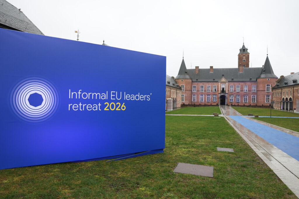 Großes blaues Schild mit weißem Text 'Informal EU leaders' retreat 2026' vor einem historischen Schlossgebäude mit Türmen und einem Wassergraben